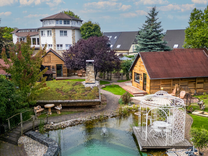 Blick über den Schlossteich auf die Chalets im Hotelgarten. Direkt angrenzend befindet sich die MaaSauna.