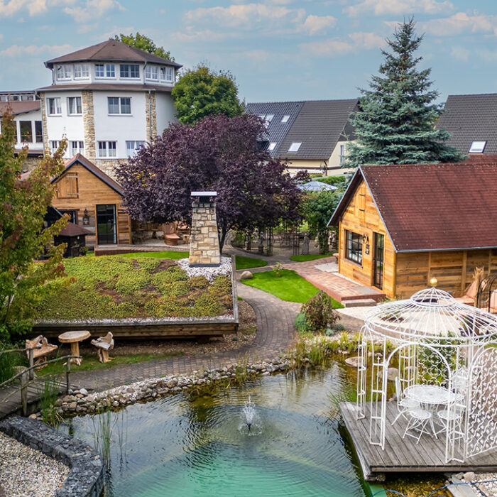 Blick über den Schlossteich auf die Chalets im Hotelgarten. Direkt angrenzend befindet sich die MaaSauna.