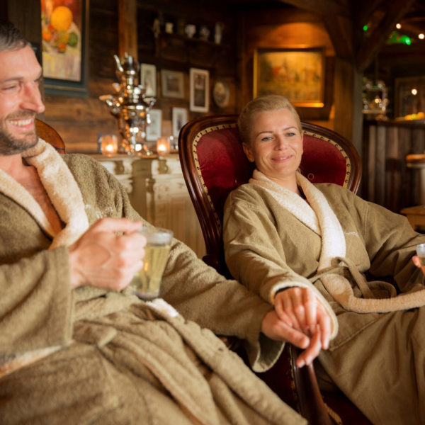 Paar in Bademänteln mit Teegläsern